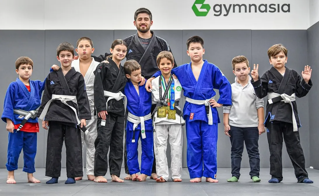 Younger Gymnasia students in gi with their coach after a session